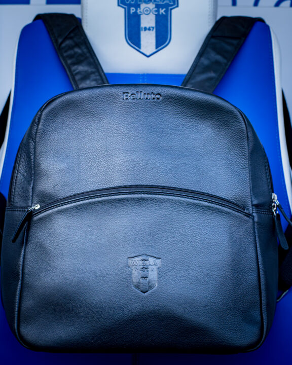 Czarny skórzany plecak z herbem Wisły Płock leży na tle niebieskiego siedzenia.